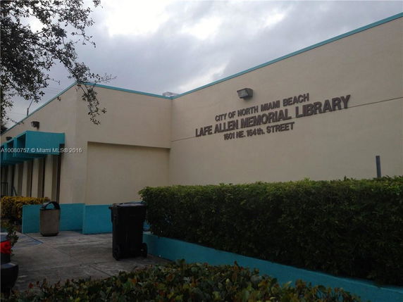 Front view of a single-story library building with a flat roof and beige walls.