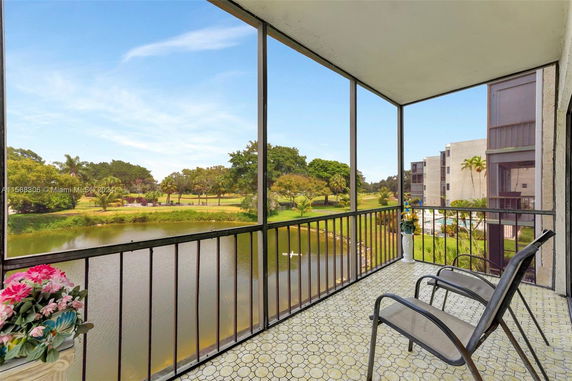 Balcony with chairs overlooking a scenic view of a pond and green landscape.