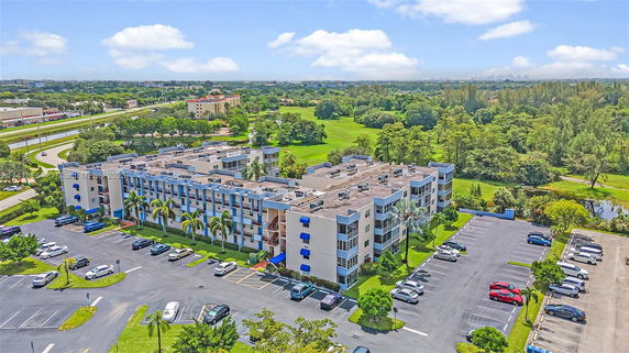 Aerial view of a multi-story residential building with parking lots and green areas.