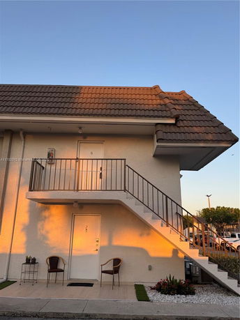 Front view of a two-story building with an external staircase and a tile roof.