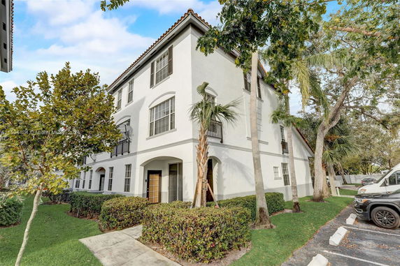 Front view of a multi-story residential building with a white exterior and a tiled roof.
