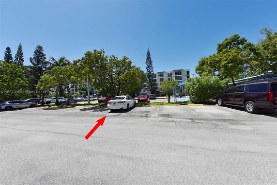 Outdoor parking area with multiple cars and trees.