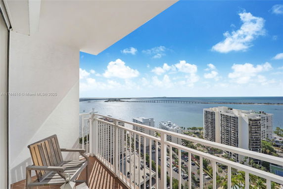 Panoramic view from a balcony overlooking a body of water and city buildings.