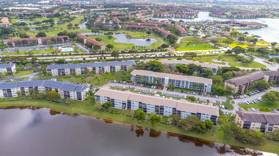 Aerial view of residential buildings near a water body with surrounding landscape.