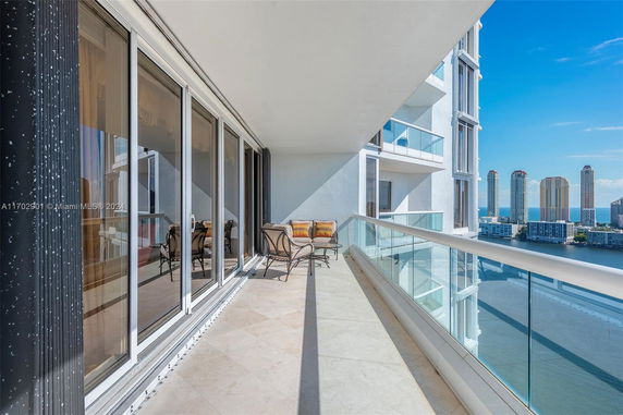 Balcony with glass railing overlooking a cityscape and water.