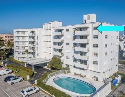 Front view of a multi-story apartment building with balconies and a swimming pool.