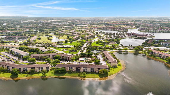 Aerial view of a residential area with multi-story buildings surrounded by greenery and water bodies.