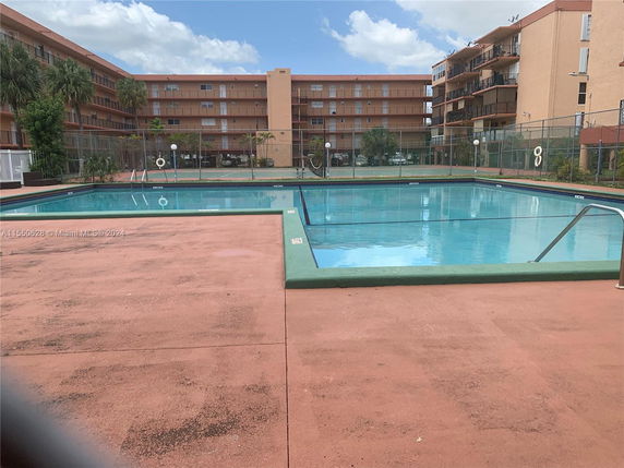 Outdoor swimming pool area with apartment buildings in the background.