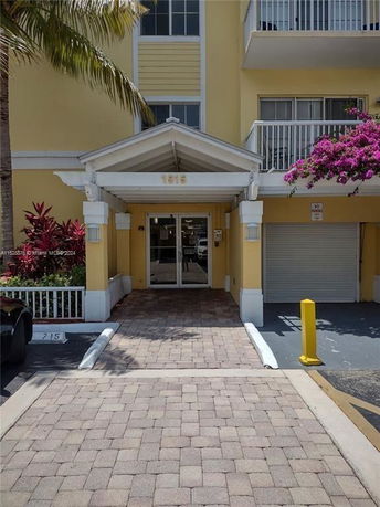 Front view of a building entrance with a small portico and glass doors.