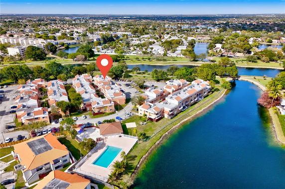 Aerial view of a residential area with a swimming pool and waterway.
