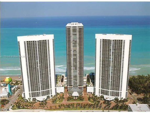 Elevated view of three high-rise buildings by the sea.