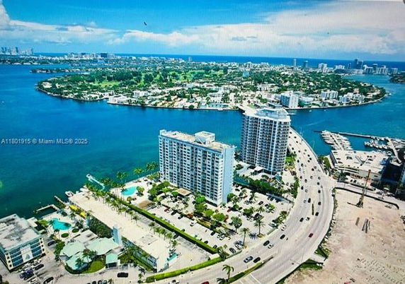 Aerial view of multiple tall residential buildings overlooking a body of water with a road running alongside.