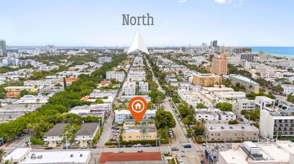 Aerial panoramic view of an urban area with multiple residential and commercial buildings, roads, and distant cityscape.