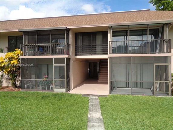Front view of a multi-story building with screened balconies and a central staircase.