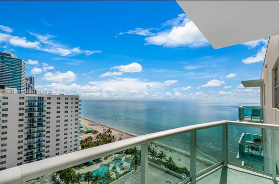 Panoramic view of beachfront and ocean from a high-rise balcony.