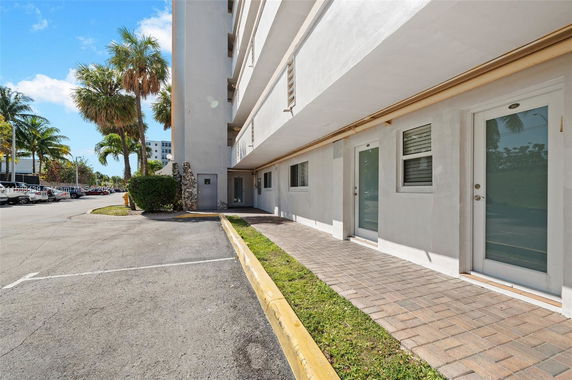 Side view of a multi-story building with glass doors and parking spaces.
