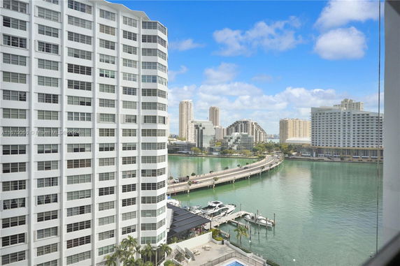 View of a waterfront cityscape with high-rise buildings and a bridge over water.