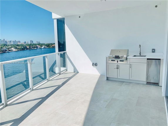 Terrace with outdoor kitchen features, overlooking a waterfront and city skyline.