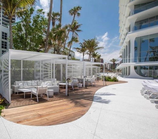Outdoor seating area with modern architecture and palm trees.