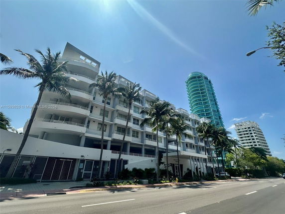 Front view of a multi-story building with balconies and palm trees.