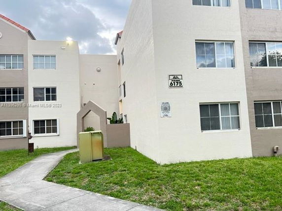Front view of a multi-story apartment building with a cream and brown facade.