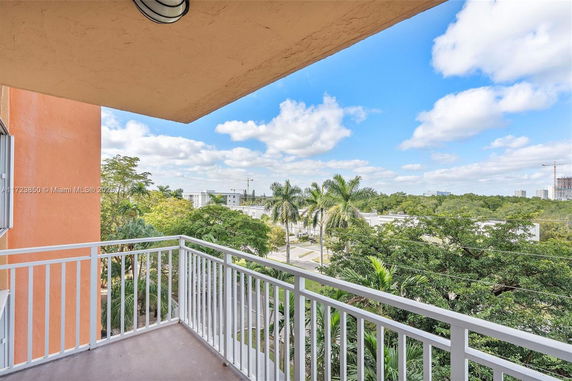 Balcony view overlooking green trees and buildings in the distance.
