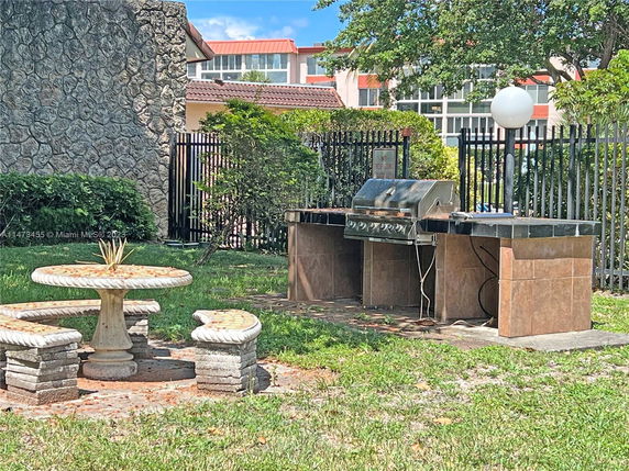 Outdoor area with a stone table, benches, and a built-in barbecue grill.