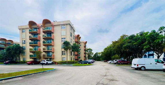 Parking area in front of a mid-rise residential building.