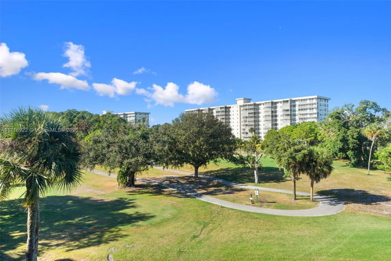 View of a multi-story residential building surrounded by greenery and trees.