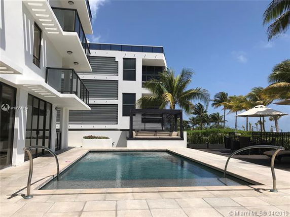 Outdoor swimming pool in front of a modern multi-story building.