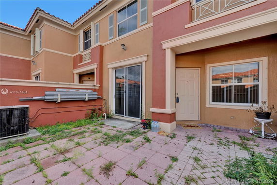 Front view of a two-story house with a sliding glass door and tiled patio.