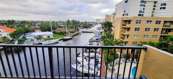 Panoramic view from a building balcony showing a waterfront with boats and surrounding structures.