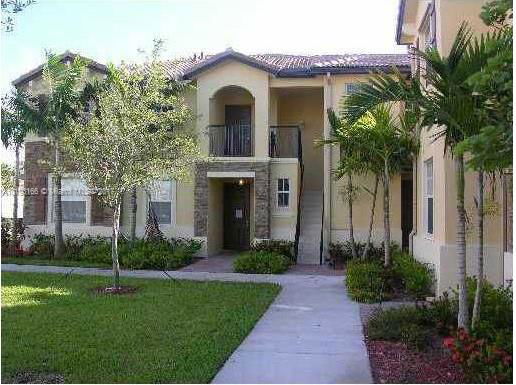 Front view of a multi-story building with a balcony and stucco exterior.