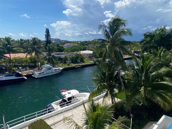 View of canal with boats and palm trees in a residential area.