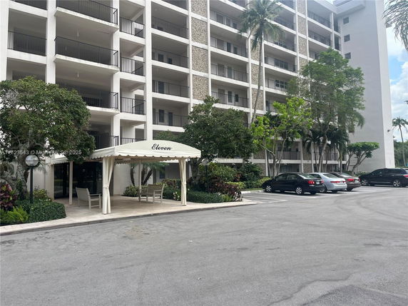 Front view of a multi-story residential building with balconies and a white canopy entrance.