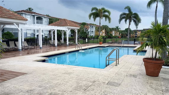 Outdoor swimming pool area with lounge chairs and a pergola.
