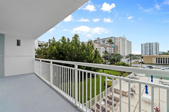 View from a balcony overlooking a pool area and nearby buildings.