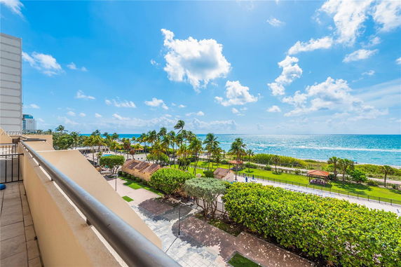 Panoramic view from a building overlooking the ocean and palm trees.