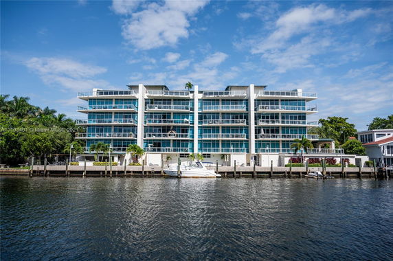 Front view of a multi-story waterfront building with balconies.