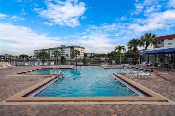 Outdoor swimming pool area with lounge chairs and umbrellas.