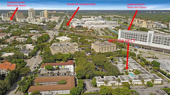 Aerial panoramic view of a city area with buildings, roads, and a metro station visible.