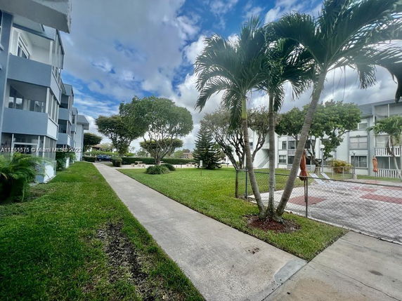 View of residential buildings with adjacent grassy area and walkway.