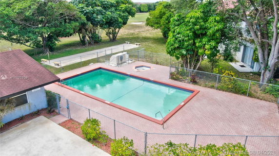 Outdoor swimming pool with surrounding fence and adjacent structure.