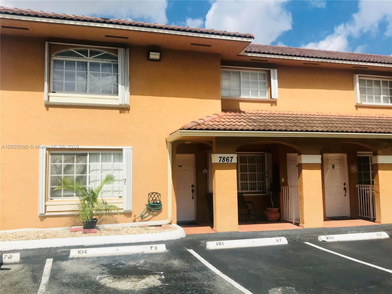 Front view of a two-story building with a tiled roof and arched entrance.