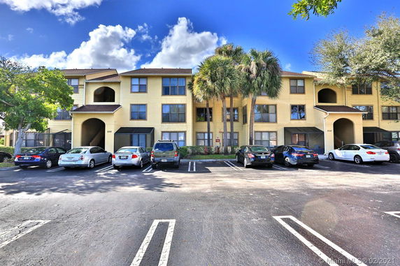 Front view of a multi-story residential building with parking spaces.