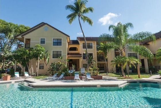 Outdoor view of a multi-story residential building with a swimming pool in front.