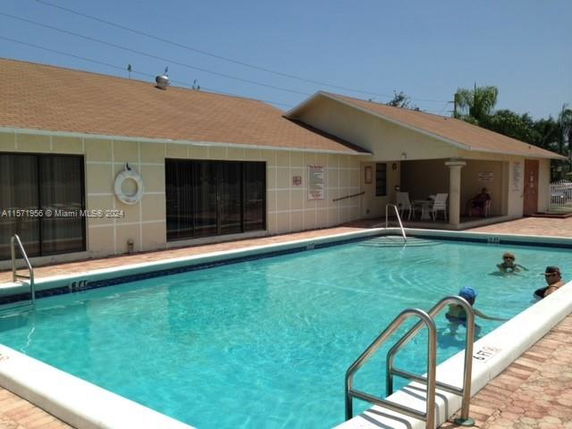 Outdoor swimming pool next to a single-story building.