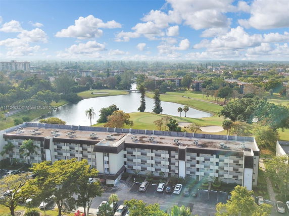 Panoramic view of a building with surrounding landscape and water body.