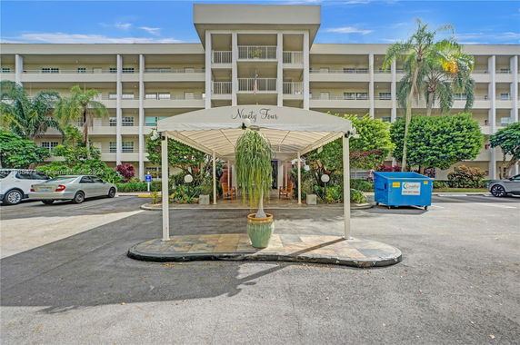 Front view of a multi-story building with a covered entrance and parking area.
