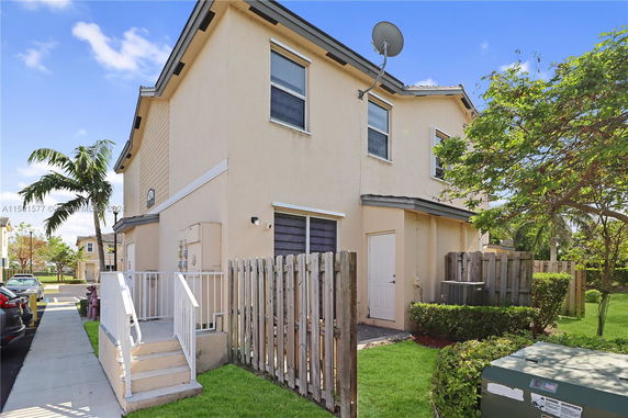 Front view of a two-story beige house with a satellite dish on the side.